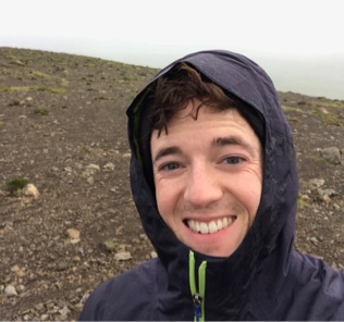 A smiling photo of josh with a rain jacket on.